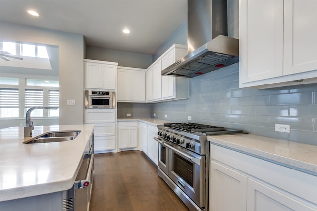 kitchen featuring wall chimney range hood, white cabinets, dark hardwood / wood-style flooring, appliances with stainless steel finishes, and sink