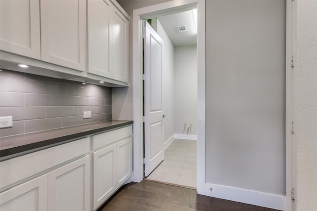 bar featuring white cabinetry, dark hardwood / wood-style floors, and backsplash