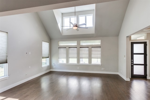 unfurnished living room featuring ceiling fan, a healthy amount of sunlight, high vaulted ceiling, and dark hardwood / wood-style flooring