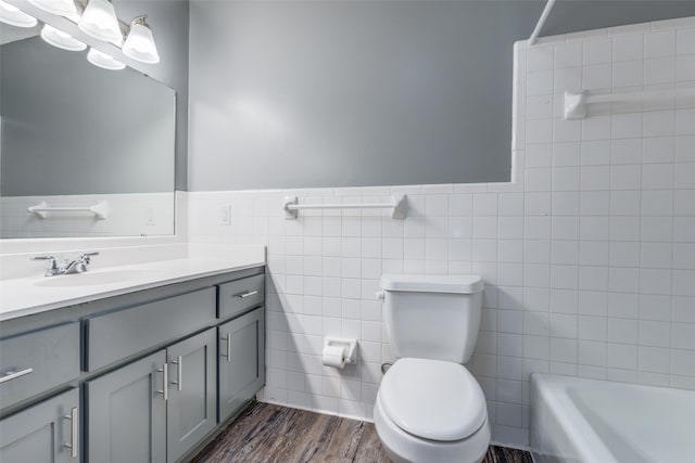 full bathroom with shower / bathing tub combination, toilet, tile walls, vanity, and hardwood / wood-style flooring