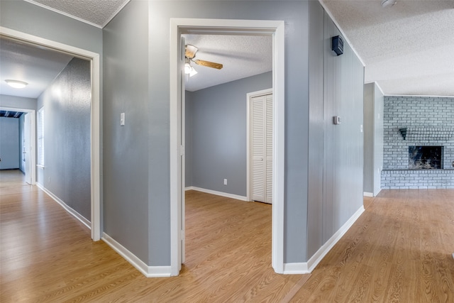 corridor with light hardwood / wood-style floors and a textured ceiling