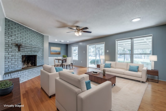 living room featuring a fireplace, light wood-type flooring, and ceiling fan