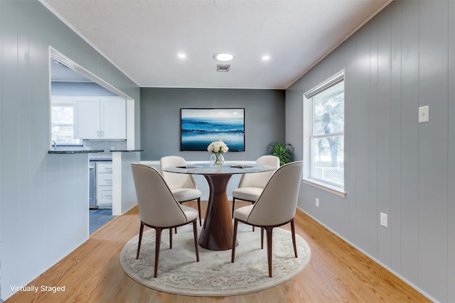 dining space featuring light hardwood / wood-style flooring and wood walls