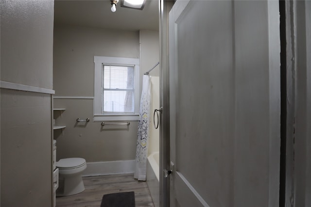 bathroom featuring shower / bathtub combination with curtain, toilet, and hardwood / wood-style floors