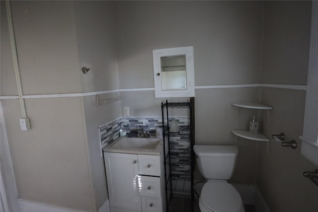 bathroom featuring vanity, toilet, and decorative backsplash