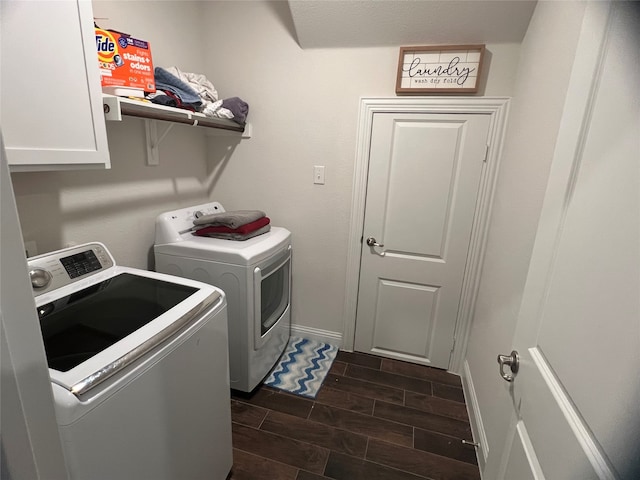 washroom featuring cabinets, washing machine and dryer, and dark hardwood / wood-style flooring