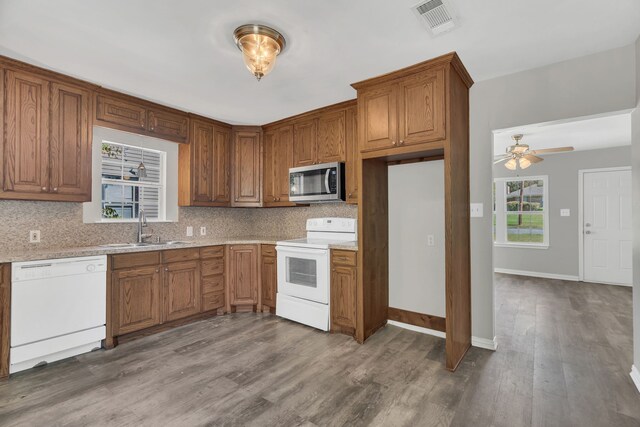 kitchen with dark hardwood / wood-style flooring, decorative backsplash, a wealth of natural light, and white appliances