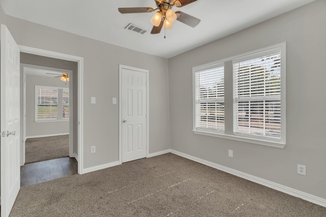 unfurnished bedroom with multiple windows, carpet floors, and ceiling fan