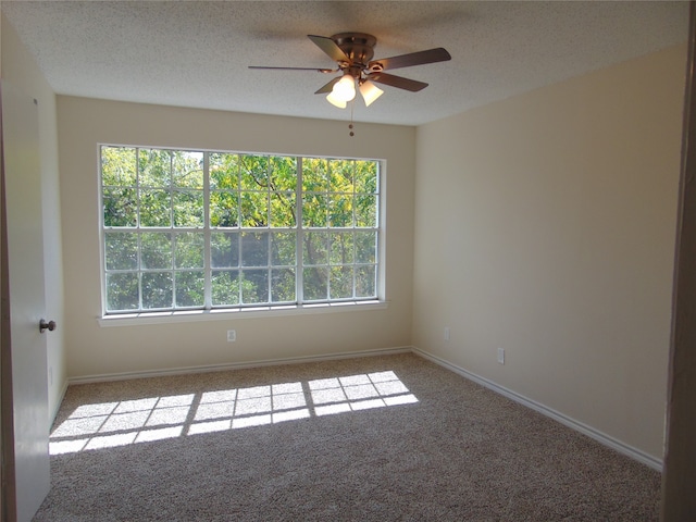 carpeted spare room featuring a textured ceiling, plenty of natural light, and ceiling fan