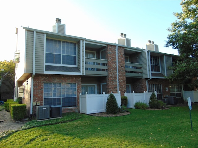 back of house with central AC and a lawn