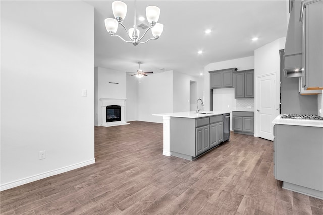 kitchen with hardwood / wood-style flooring, gray cabinets, and a kitchen island with sink