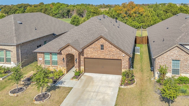 view of front of house with central air condition unit, a front lawn, and a garage