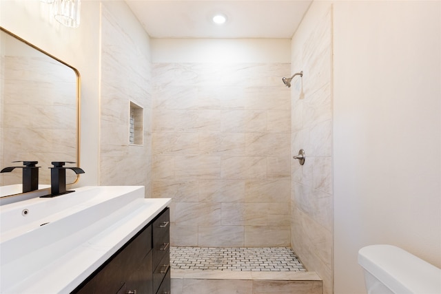 bathroom with tiled shower, vanity, and toilet