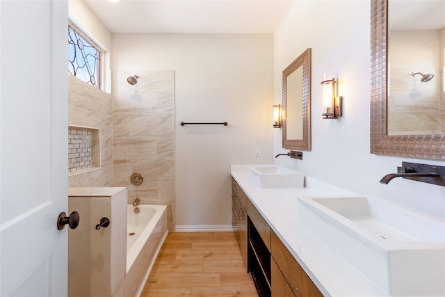 bathroom with hardwood / wood-style floors, vanity, and tiled shower / bath combo