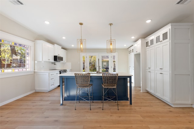 kitchen with a center island with sink, white cabinets, and stainless steel appliances