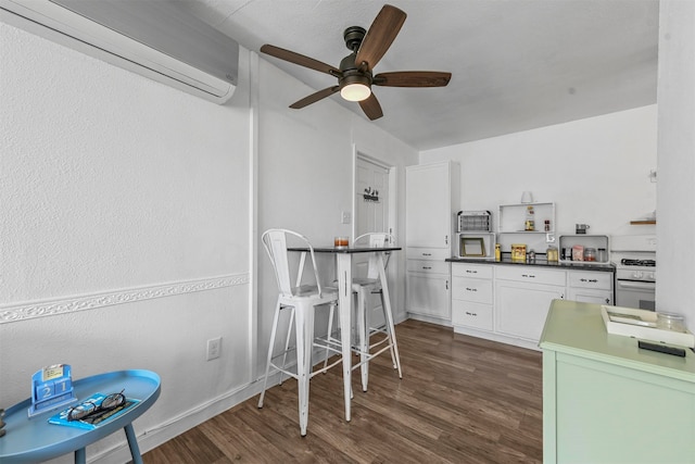 kitchen featuring ceiling fan, white stove, white cabinets, a wall mounted AC, and dark hardwood / wood-style floors