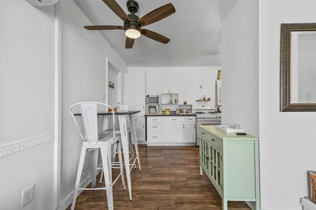 kitchen featuring white range, dark wood-type flooring, green cabinets, white cabinetry, and ceiling fan