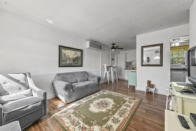 living room with an AC wall unit, dark wood-type flooring, and ceiling fan