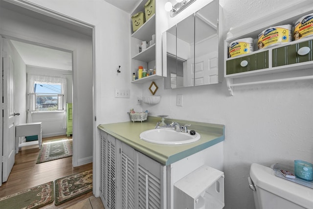 bathroom with toilet, a textured ceiling, vanity, and wood-type flooring