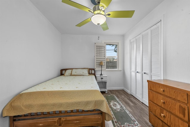 bedroom with crown molding, dark hardwood / wood-style floors, a closet, and ceiling fan