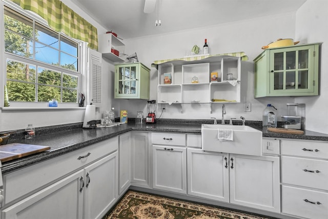 kitchen with sink, white cabinets, crown molding, and ceiling fan