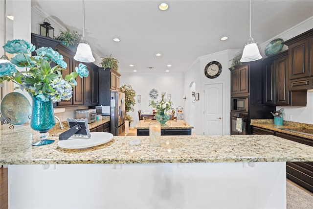 kitchen with black appliances, a center island, dark brown cabinetry, and ornamental molding