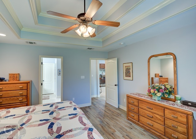 bedroom with ceiling fan, crown molding, a tray ceiling, and light hardwood / wood-style floors