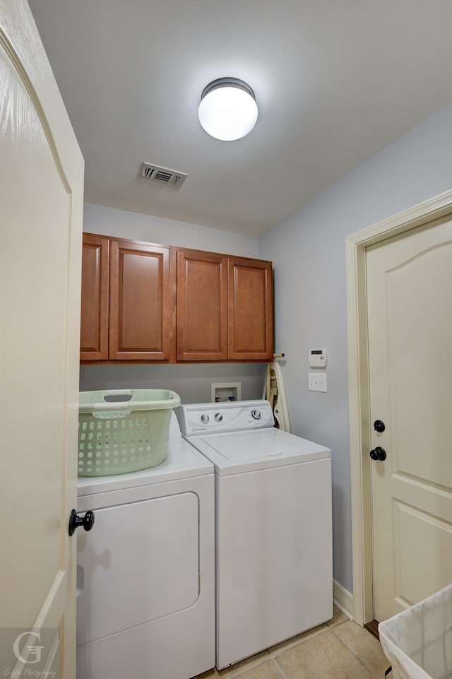 washroom featuring light tile patterned floors, washing machine and dryer, and cabinets