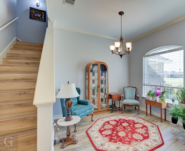 sitting room with an inviting chandelier, crown molding, and wood-type flooring