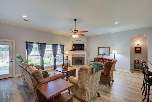 living room with a wealth of natural light, ornamental molding, light hardwood / wood-style flooring, and ceiling fan