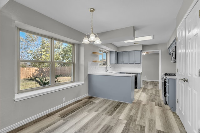 kitchen featuring backsplash, kitchen peninsula, gas stove, and a healthy amount of sunlight