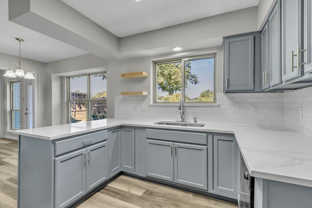 kitchen with gray cabinets, sink, kitchen peninsula, and light wood-type flooring