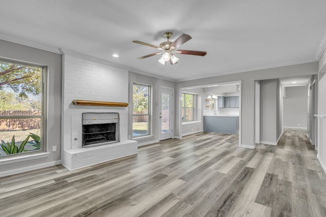 unfurnished living room with a wealth of natural light, crown molding, light hardwood / wood-style flooring, and a fireplace