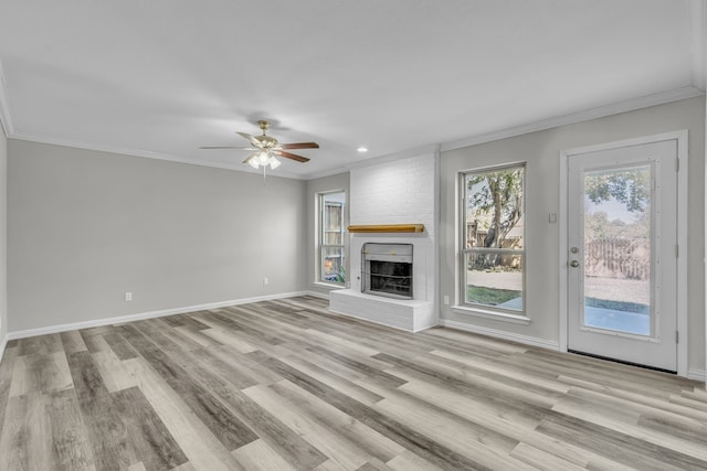 unfurnished living room featuring light hardwood / wood-style floors, ornamental molding, a brick fireplace, and ceiling fan