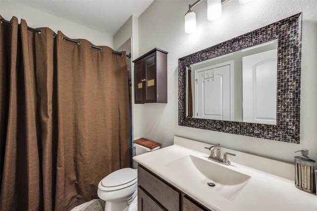 bathroom with walk in shower, vanity, and toilet