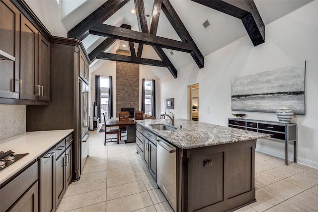 kitchen with an island with sink, dark brown cabinets, sink, and stainless steel dishwasher