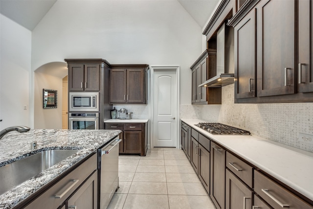 kitchen with sink, high vaulted ceiling, backsplash, light tile patterned floors, and appliances with stainless steel finishes