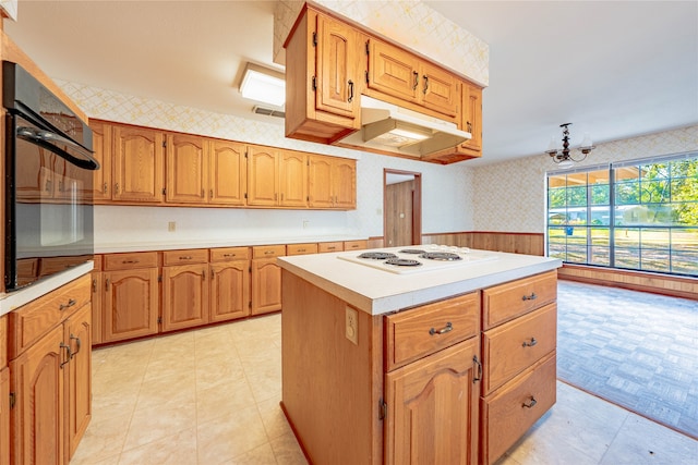 kitchen featuring wood walls, a chandelier, a center island, white electric stovetop, and black oven