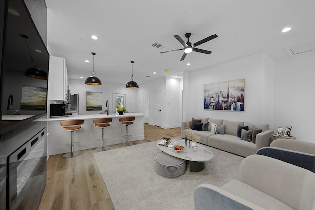 living room with light wood-type flooring, sink, and ceiling fan