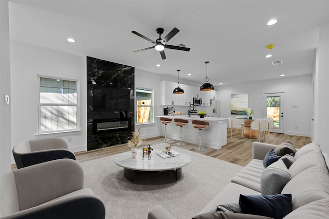 living room with light hardwood / wood-style floors, ceiling fan, and sink