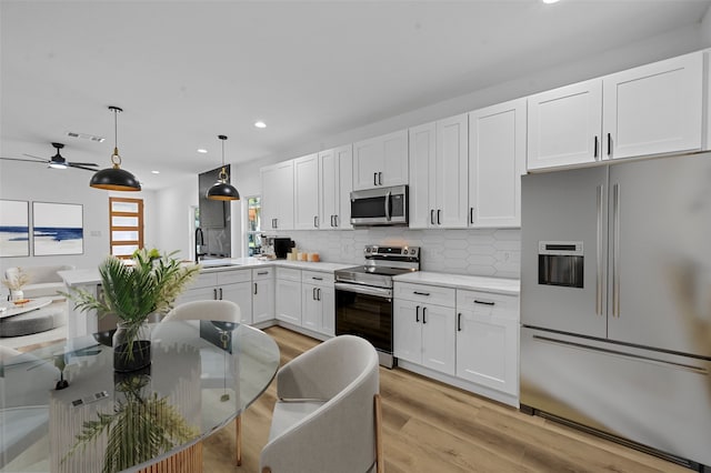 kitchen featuring stainless steel appliances, light hardwood / wood-style floors, pendant lighting, tasteful backsplash, and white cabinetry