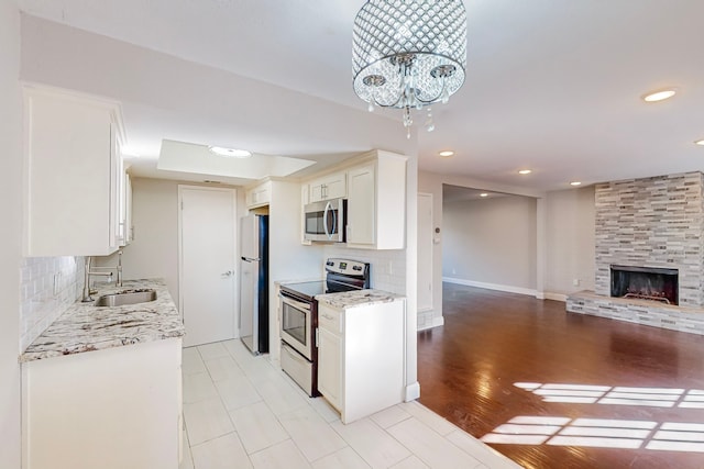 kitchen with tasteful backsplash, white cabinetry, sink, light hardwood / wood-style floors, and stainless steel appliances