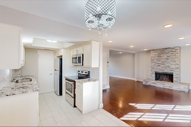 kitchen with sink, light hardwood / wood-style floors, stainless steel appliances, white cabinets, and an inviting chandelier