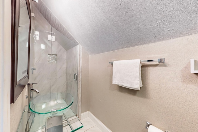 bathroom with a shower with door, lofted ceiling, a textured ceiling, and tile patterned flooring