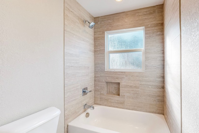 bathroom with toilet and tiled shower / bath combo