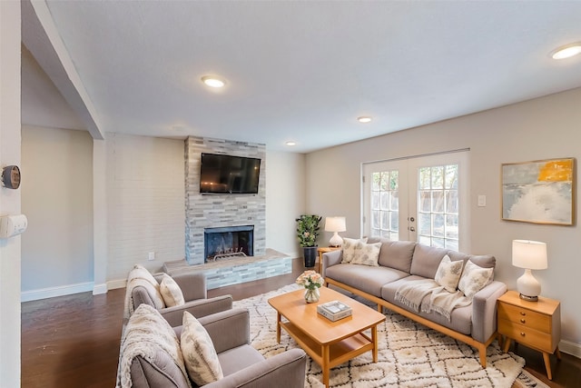 living room featuring french doors, a stone fireplace, and wood-type flooring