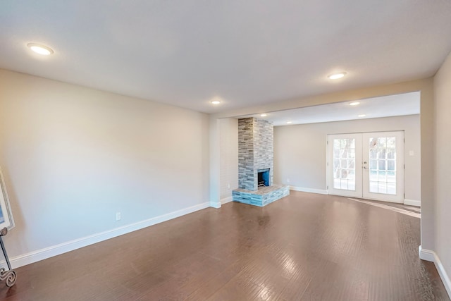 unfurnished living room with dark wood-type flooring, french doors, and a fireplace