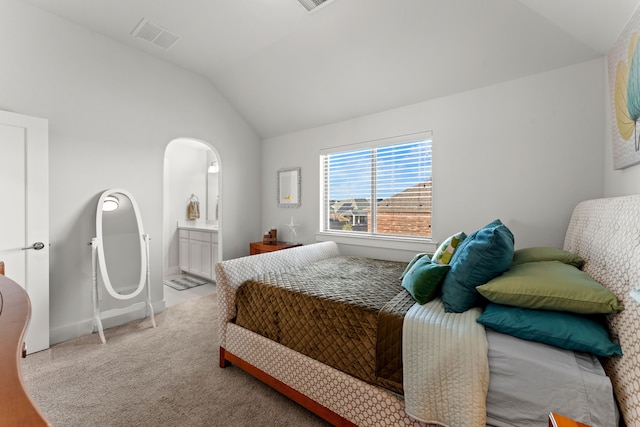 bedroom with ensuite bath, light carpet, and lofted ceiling