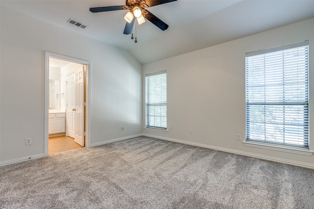 unfurnished bedroom featuring ceiling fan, light carpet, ensuite bath, and vaulted ceiling