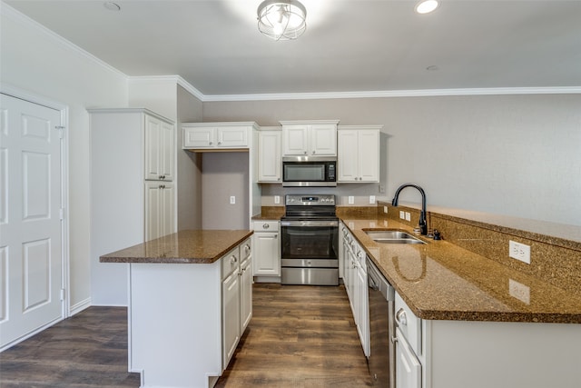 kitchen with white cabinets, appliances with stainless steel finishes, dark stone counters, sink, and ornamental molding